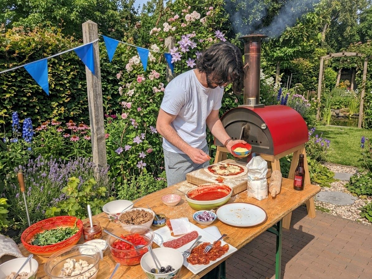 Pizza beleggen aan tafel tussen de bloemen naast de oven